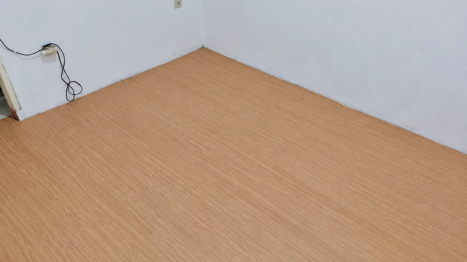 Foto pemasangan lantai vinyl Timberwood motif kayu di ruangan kosong, dengan pencahayaan dan ketajaman ditingkatkan menggunakan AI